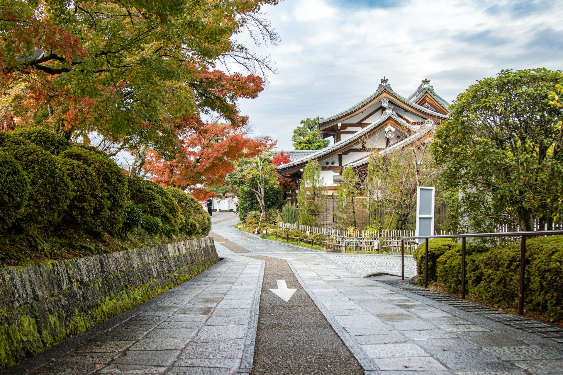 Paved road in Kyoto, Japan, featuring a directional sign indicating nearby attractions or locations.