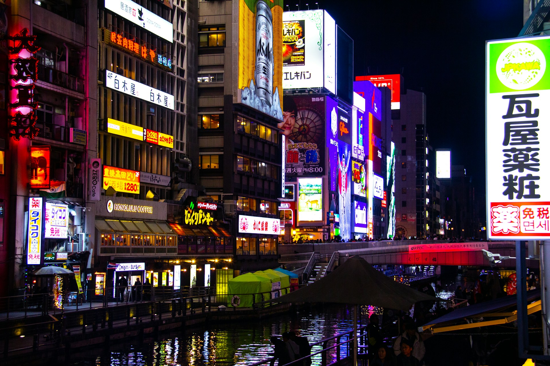 A scenic view of a river flowing through the city of Osaka, Japan, with buildings and greenery along the banks.
